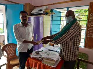 graphic கிராம நிர்வாக அலுவலரிடமிருந்து இரண்டு 500 ரூபாய் நோட்டுகள் நிவாரணமாகப் பெறும் பார்வை மாற்றுத்திறனாளி